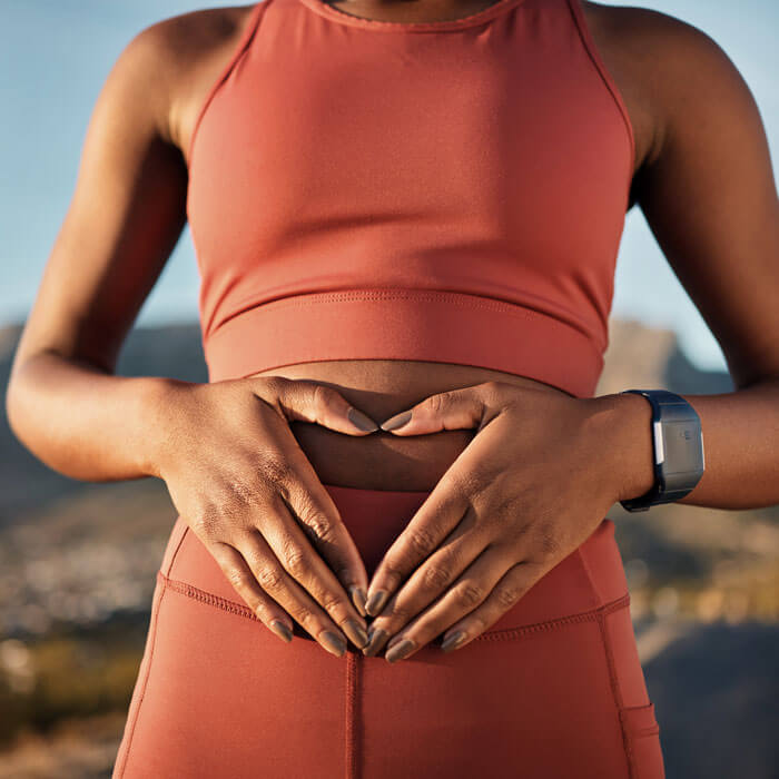 woman holding her stomach and creating a heart with her hands