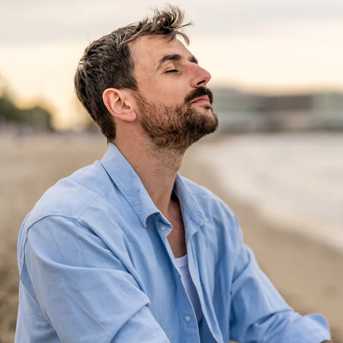 Relaxed man breathing fresh air on the beach