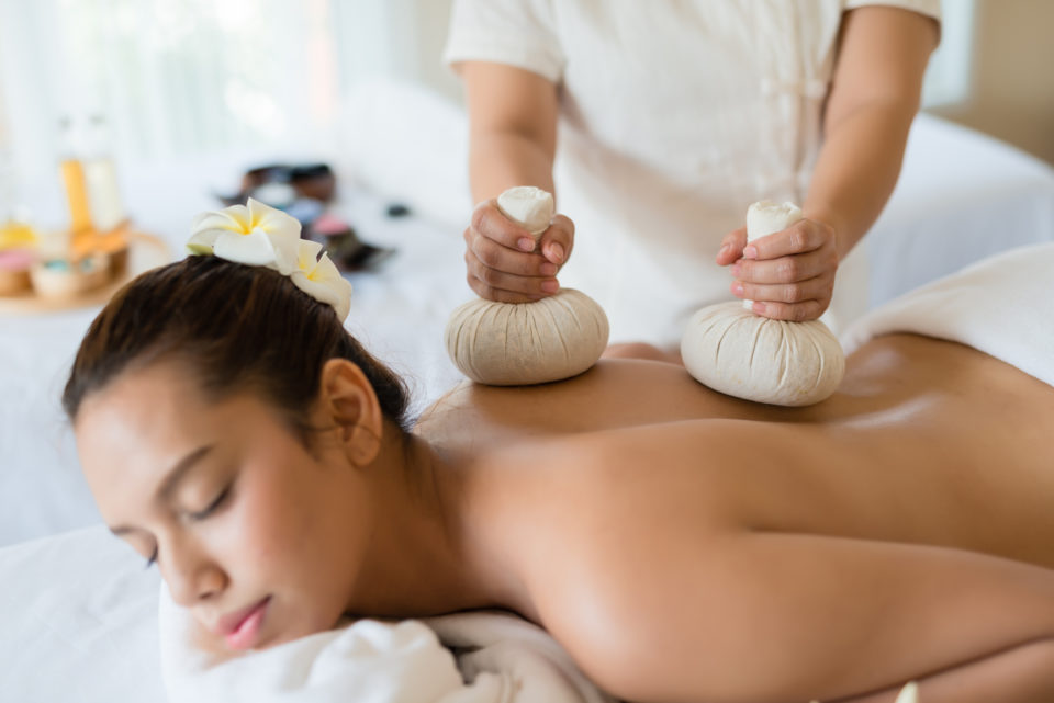 Young woman relaxing in the spa, receiving a Thai Herbal Ball Massage